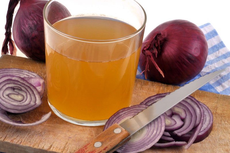 Glass of onion juice with chopped onion and knife